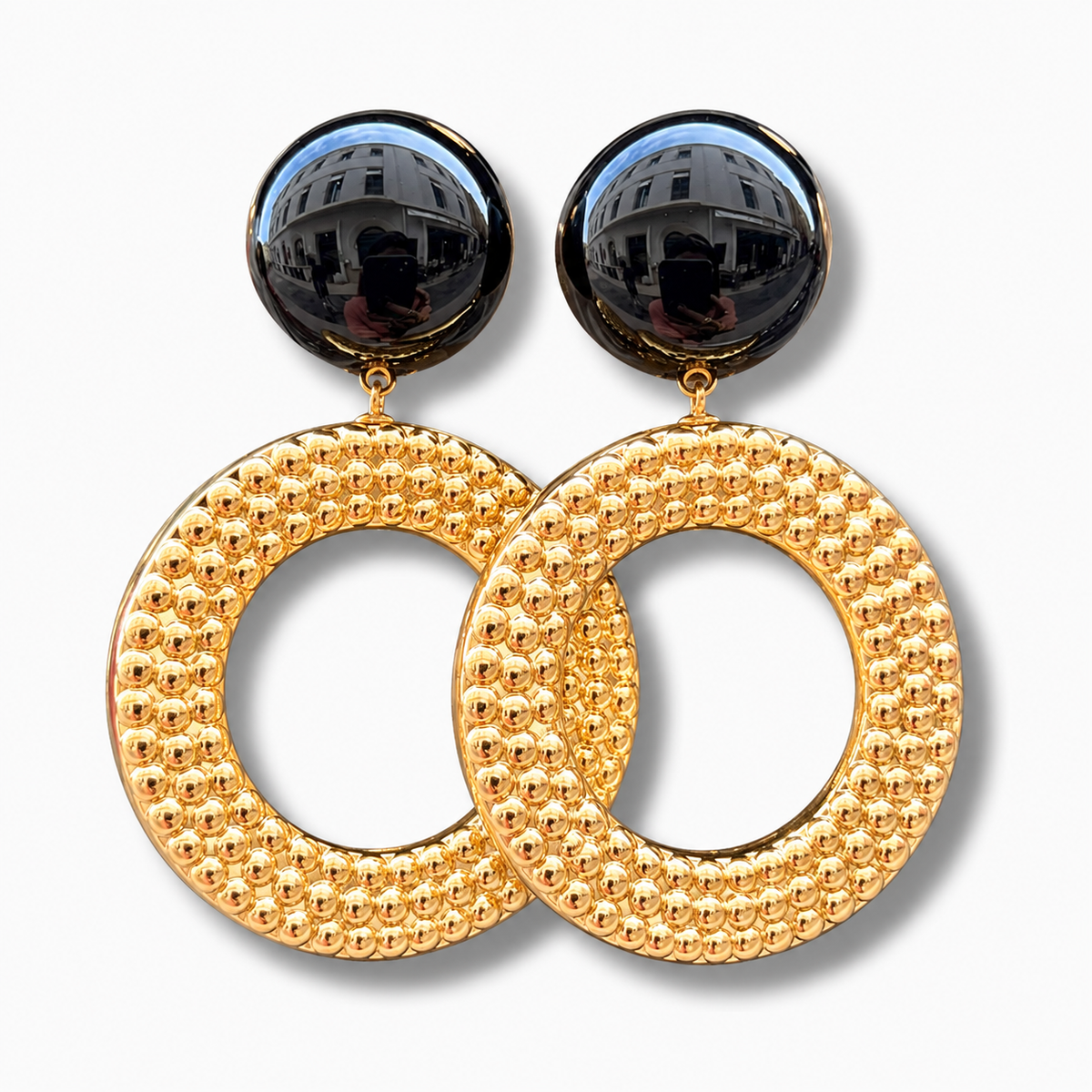 Boucles d’oreilles Avena Gold à clips Francine Bramli Paris, cabochons ronds noirs brillants et grands anneaux circulaires dorés ornés de petites perles en relief.