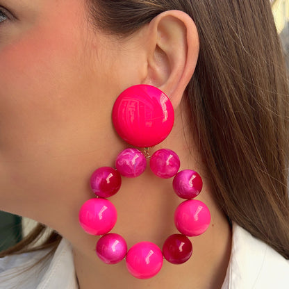 Boucles d'oreilles à clips Bastille Rose XL Francine Bramli Paris, composées d'un large bouton rond fuchsia et d'un grand anneau de perles en résine rose bonbon, framboise et fuchsia aux effets nacrés et marbrés – Divinity Sète.