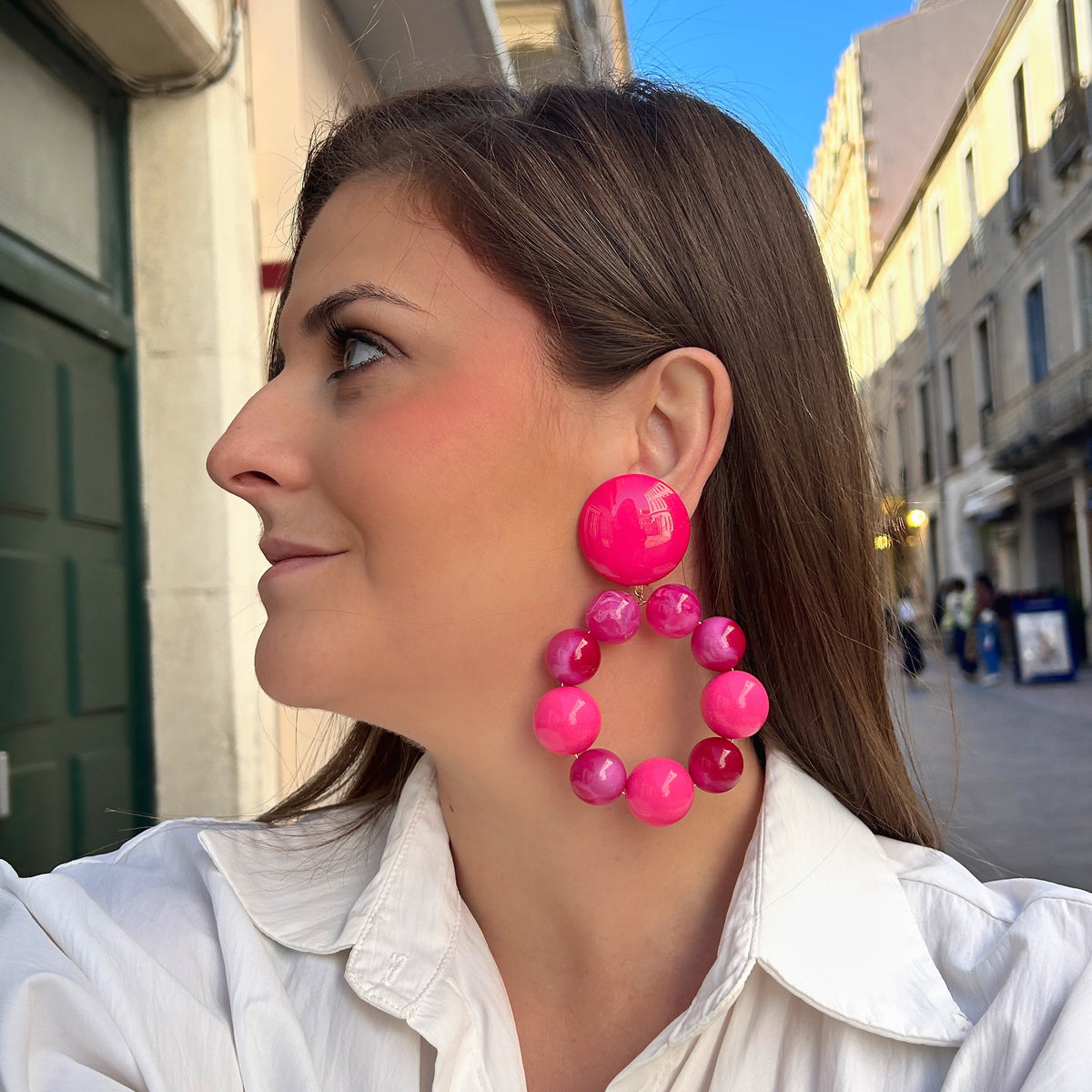 Boucles d'oreilles à clips Bastille Rose XL Francine Bramli Paris, composées d'un large bouton rond fuchsia et d'un grand anneau de perles en résine rose bonbon, framboise et fuchsia aux effets nacrés et marbrés – Divinity Sète.