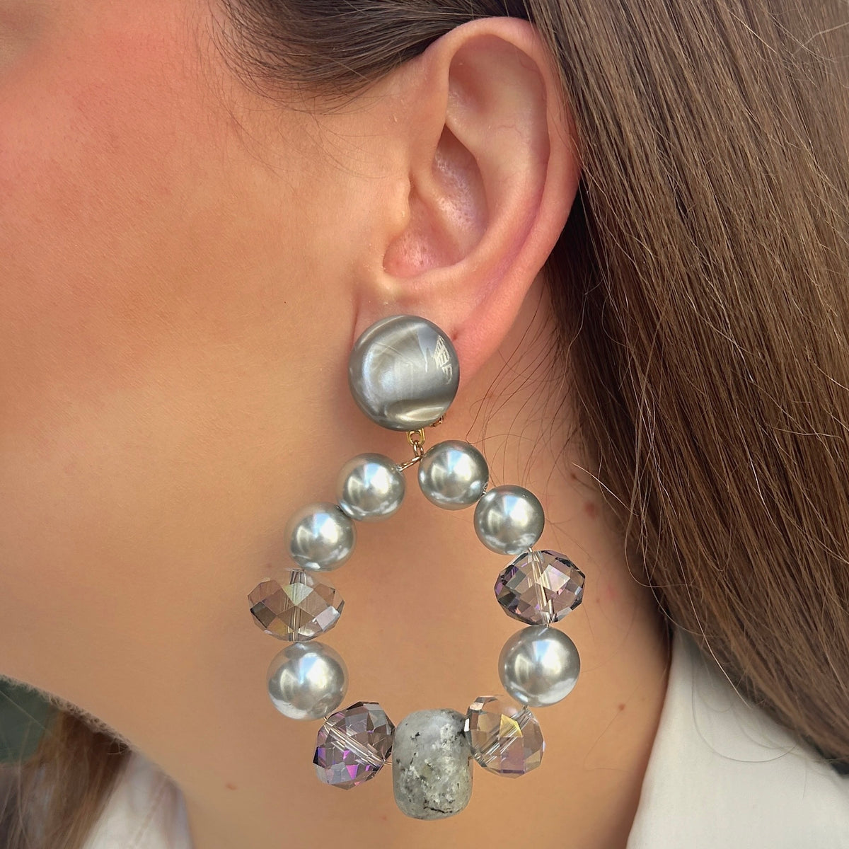 Boucles d’oreilles Bastille Silver à clips Francine Bramli Paris, grands anneaux composés de perles argentées, cristaux facettés irisés et perles minérales grises, disponibles chez Divinity Sète.