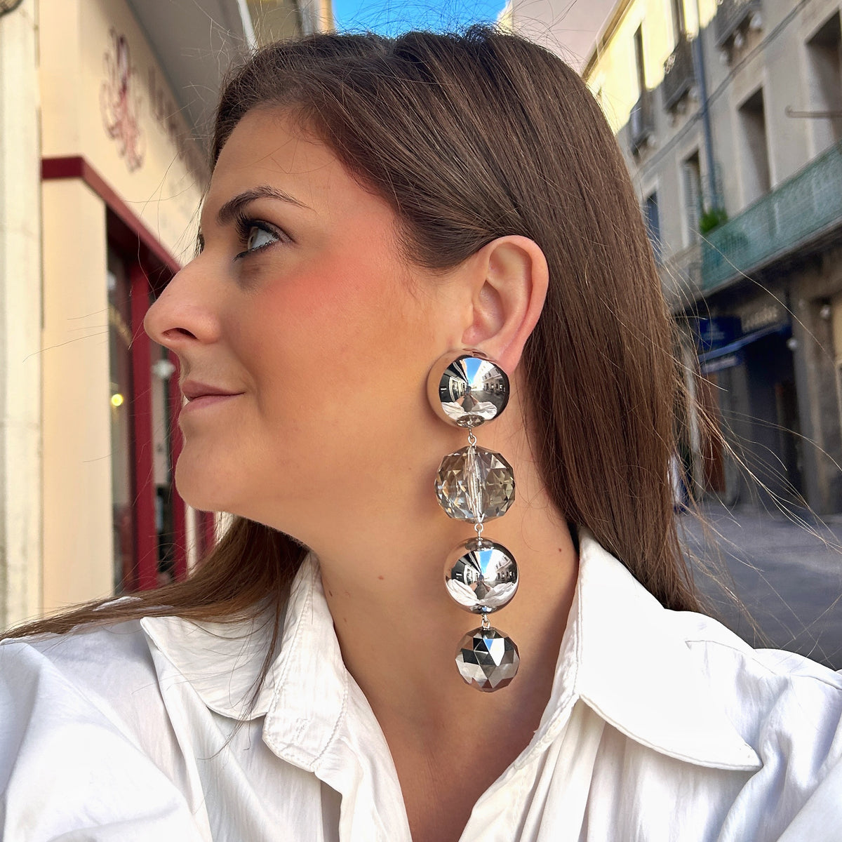 Boucles d'oreilles à clips Cascade Silver Francine Bramli Paris composées de sphères argentées effet miroir et de grosses perles facettées transparentes et gris métallisé, montées en cascade verticale – Divinity Sète.
