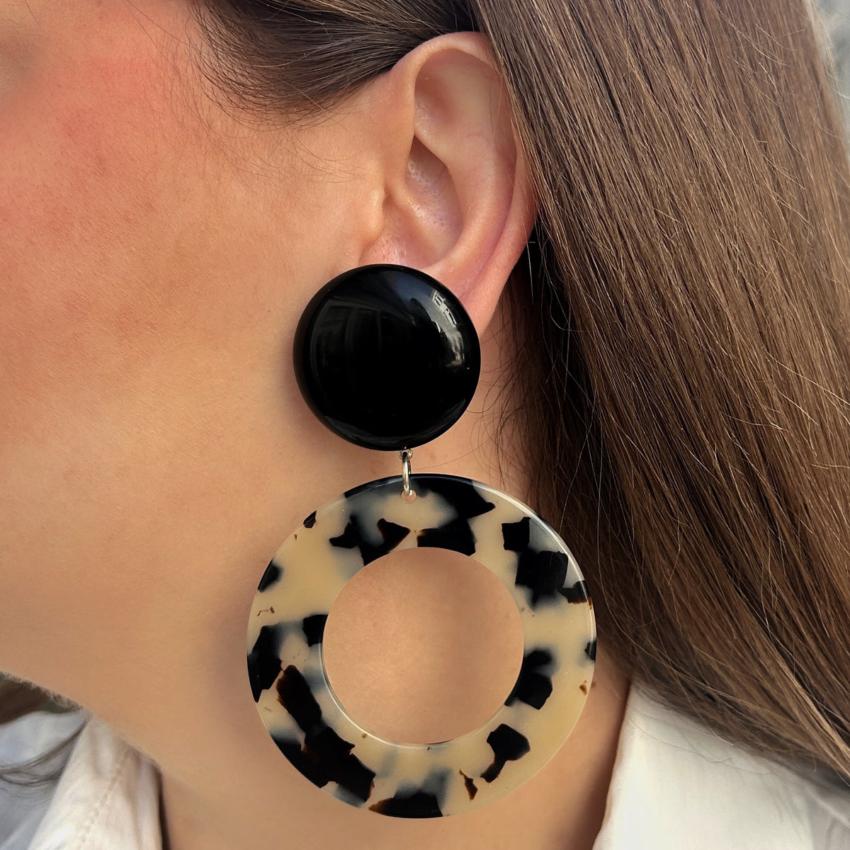 Boucles d’oreilles Cecilia à clips Francine Bramli Paris avec cabochons ronds noirs brillants et grands anneaux ajourés écaille noir et blanc.