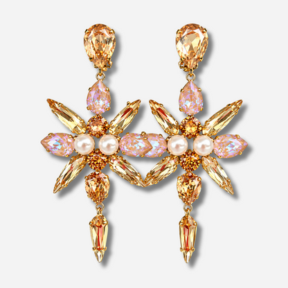 Boucles d'oreilles Celyna Gold à clips Crézus, modèle floral doré composé de cristaux facettés champagne et rose irisé en forme de goutte et de navette, avec perles blanches centrales et pampilles pendantes.
