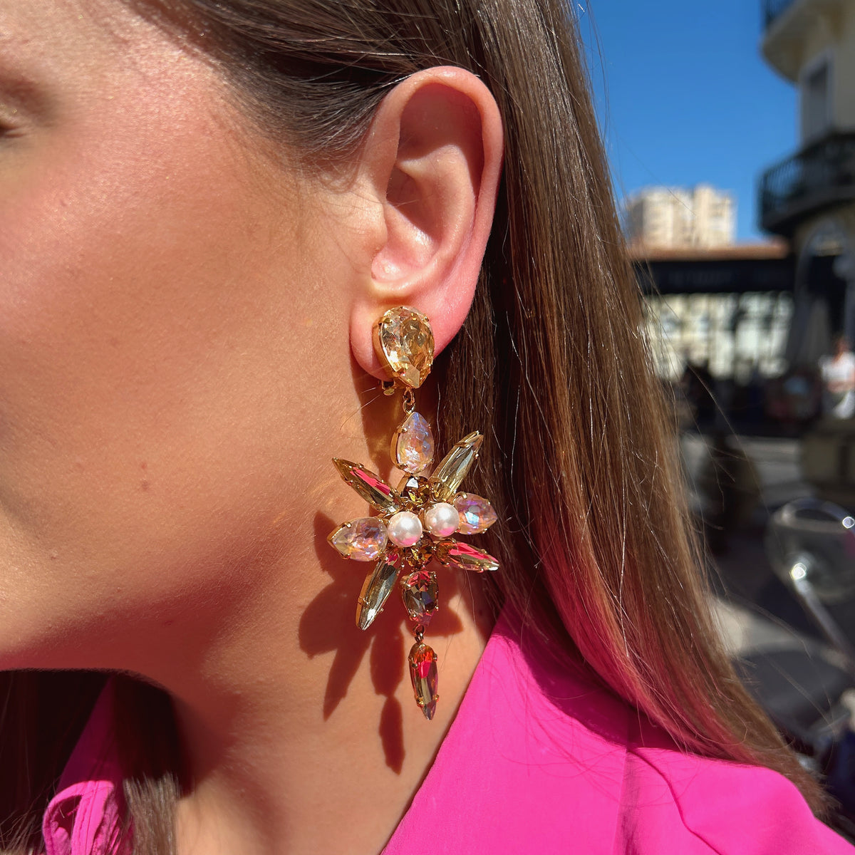 Boucles d'oreilles Celyna Gold à clips Crézus, modèle floral doré composé de cristaux facettés champagne et rose irisé en forme de goutte et de navette, avec perles blanches centrales et pampilles pendantes.