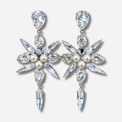 Boucles d'oreilles Celyna Silver à clips Crézus, modèle floral argenté composé de cristaux transparents facettés en forme de goutte et de navette, de trois perles blanches centrales et d'une pampille en cristal suspendue.