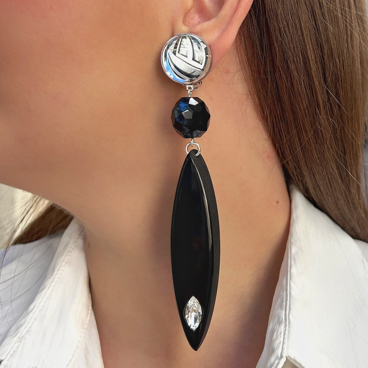 Boucles d’oreilles à clips Plume Noir Francine Bramli Paris, longues plumes en résine noire, attache miroir argenté et cristal transparent – Divinity Sète.