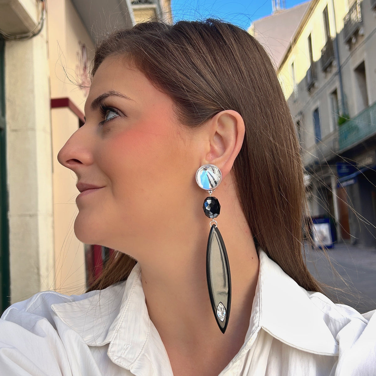 Boucles d’oreilles à clips Plume Noir Francine Bramli Paris, longues plumes en résine noire, attache miroir argenté et cristal transparent – Divinity Sète.