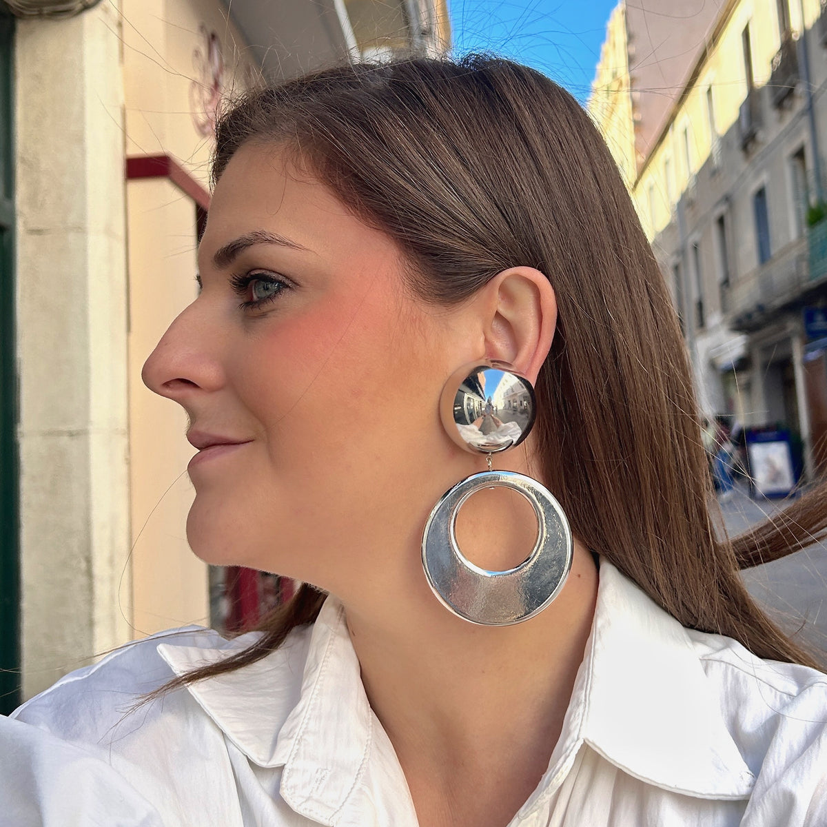 Boucles d'oreilles à clips Cloe Silver Francine Bramli Paris en résine argentée effet miroir, composées d'un gros bouton rond bombé et d'un large pendentif circulaire ajouré à finition métallisée brillante – Divinity Sète.