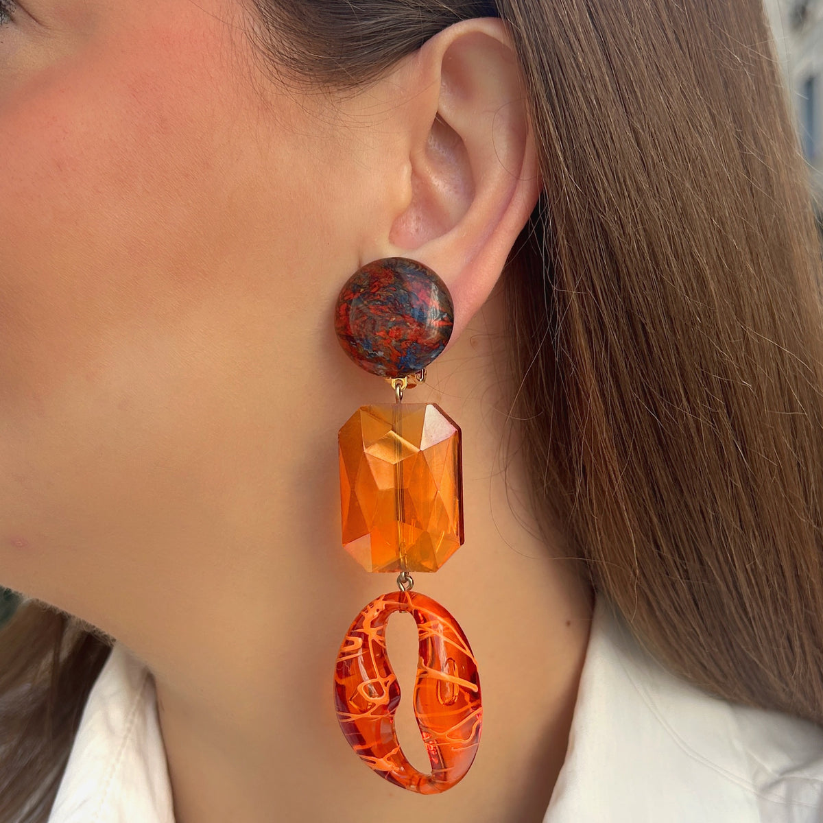 Boucles d’oreilles Dorivique Orange à clips Francine Bramli Paris, cabochons marbrés rouge et noir, cristaux rectangulaires orange facettés et pendentifs ovales ajourés.
