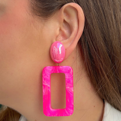 Boucles d'oreilles à clips Estelle Rose Francine Bramli Paris, clips ovales rose fuchsia et grands pendentifs rectangulaires ajourés en résine rose marbrée – Divinity Sète.