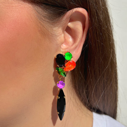 Boucles d’oreilles pendantes à clips Kalyx Fluo Crézus avec cristaux vert fluo, orange, violet et noir, longues navettes noires et montures dorées – Divinity Sète