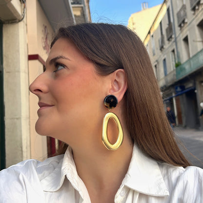 Boucles d’oreilles Lison Gold à clips Francine Bramli Paris, cabochons ronds effet écaille noir et ambre avec grands pendentifs ovales ajourés dorés brillants.