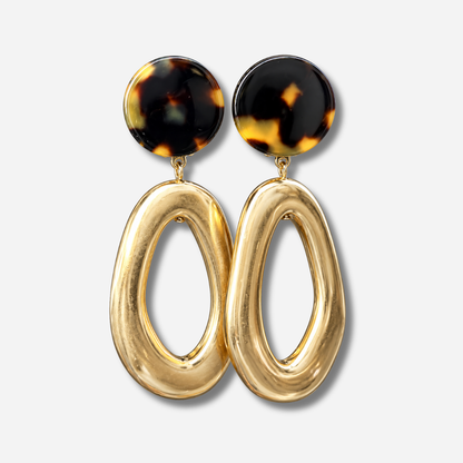 Boucles d’oreilles Lison Gold à clips Francine Bramli Paris, cabochons ronds effet écaille noir et ambre avec grands pendentifs ovales ajourés dorés brillants.
