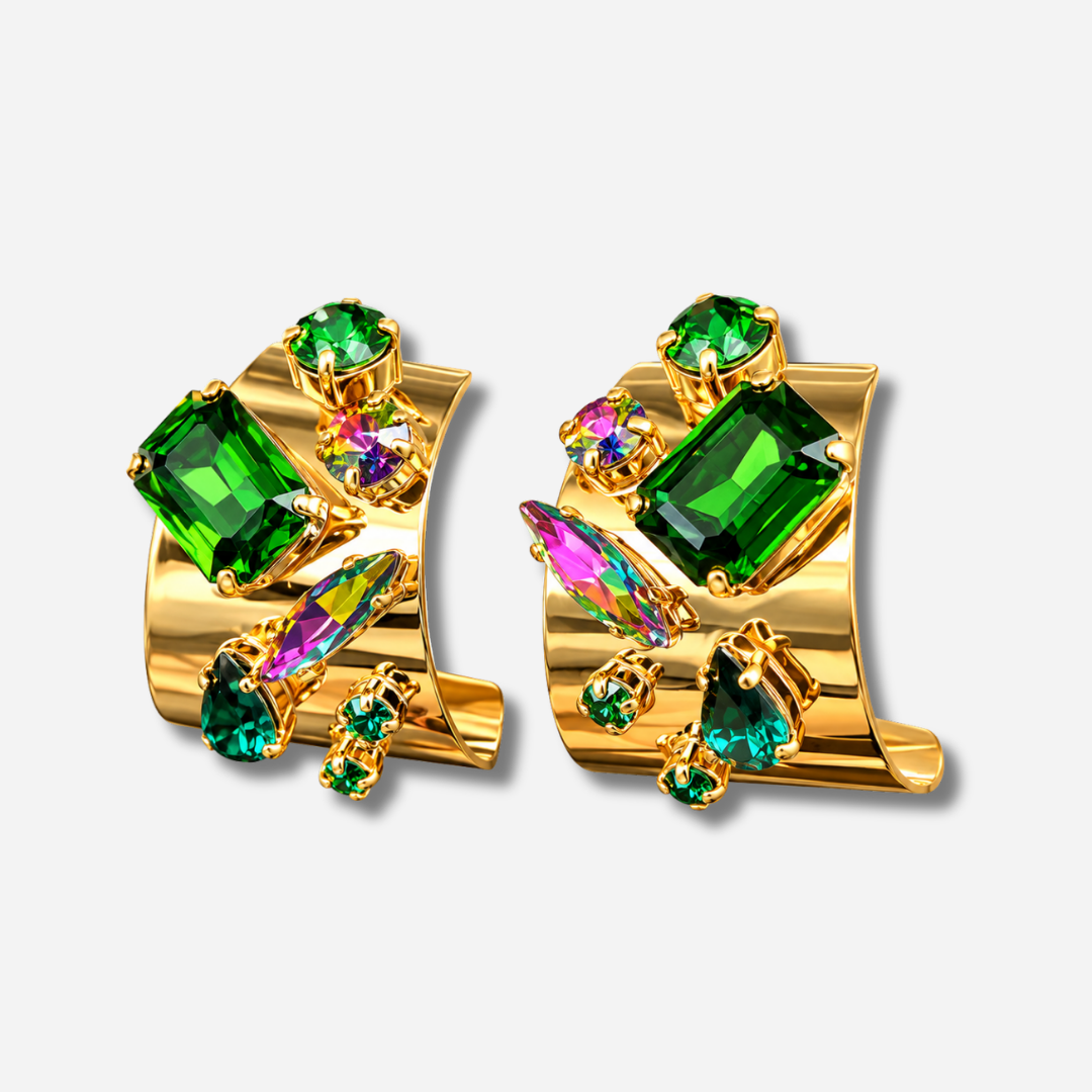 Boucles d’oreilles Lumeia Crézus à tige, monture dorée large et incurvée ornée de cristaux facettés vert émeraude, de pierres en goutte et de cristaux multicolores aux reflets roses, violets et bleus.