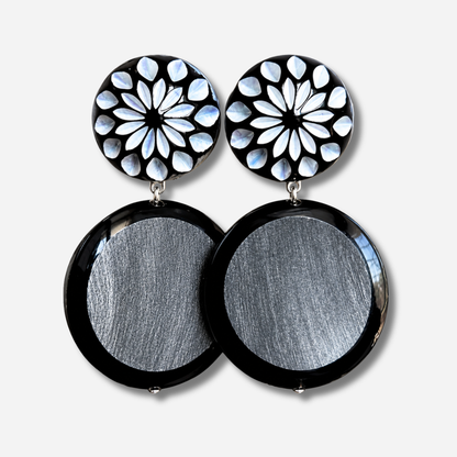 Boucles d’oreilles Maila Corne à clips Francine Bramli Paris, cabochons ronds noirs ornés de motifs floraux nacrés blancs et grands pendentifs circulaires noirs à centre argenté texturé.