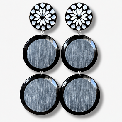 Boucles d’oreilles Maila Double Corne à clips Francine Bramli Paris, cabochons noirs à motifs floraux nacrés et deux grands pendentifs ronds noirs aux centres argentés texturés.