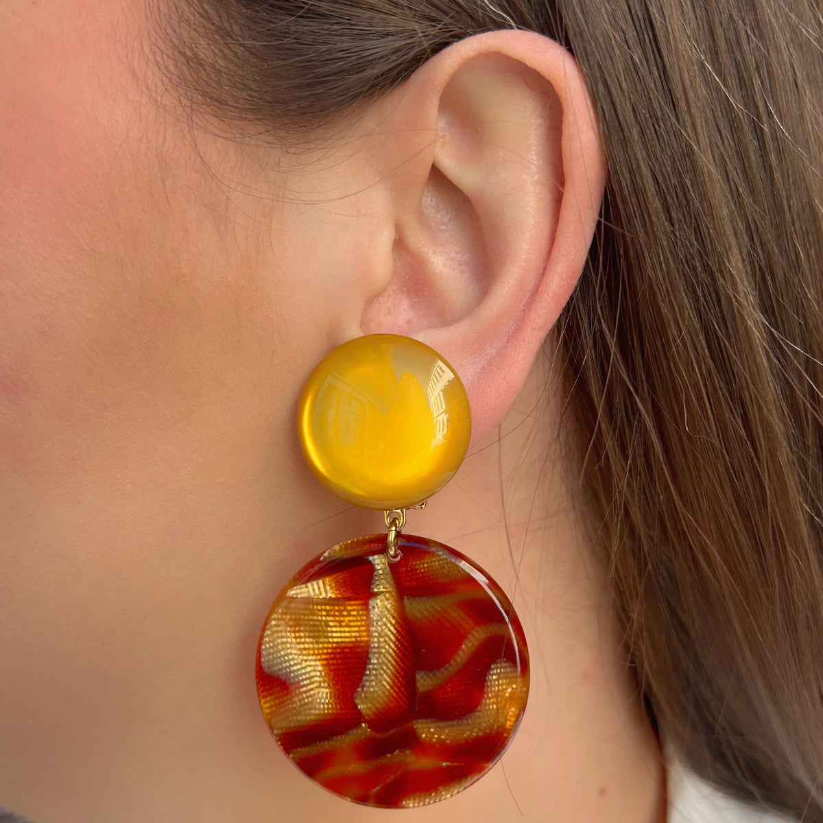 Boucles d'oreilles à clips Maila Feu Francine Bramli Paris, clips ronds jaune orangé et grands pendentifs circulaires en résine transparente aux motifs rouge feu, orange et doré – Divinity Sète.