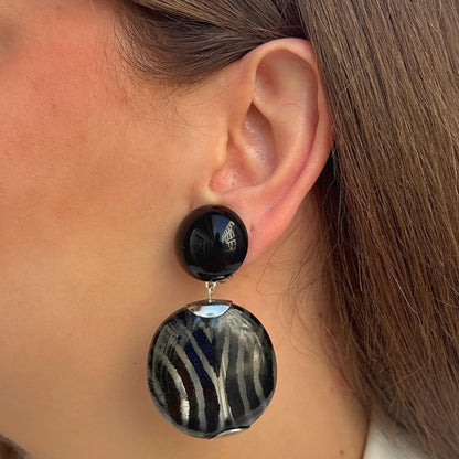 Boucles d’oreilles Mina Rayures à clips Francine Bramli Paris, cabochons noirs brillants et grands pendentifs ronds aux rayures noires et argentées.