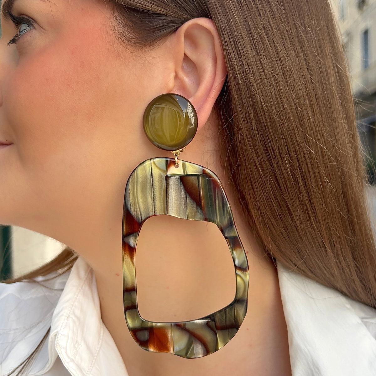 Boucles d’oreilles à clips Nerina Onyx Francine Bramli Paris, cabochons ronds kaki translucide et grands pendentifs géométriques ajourés aux nuances marbrées marron, noir, beige et vert olive.