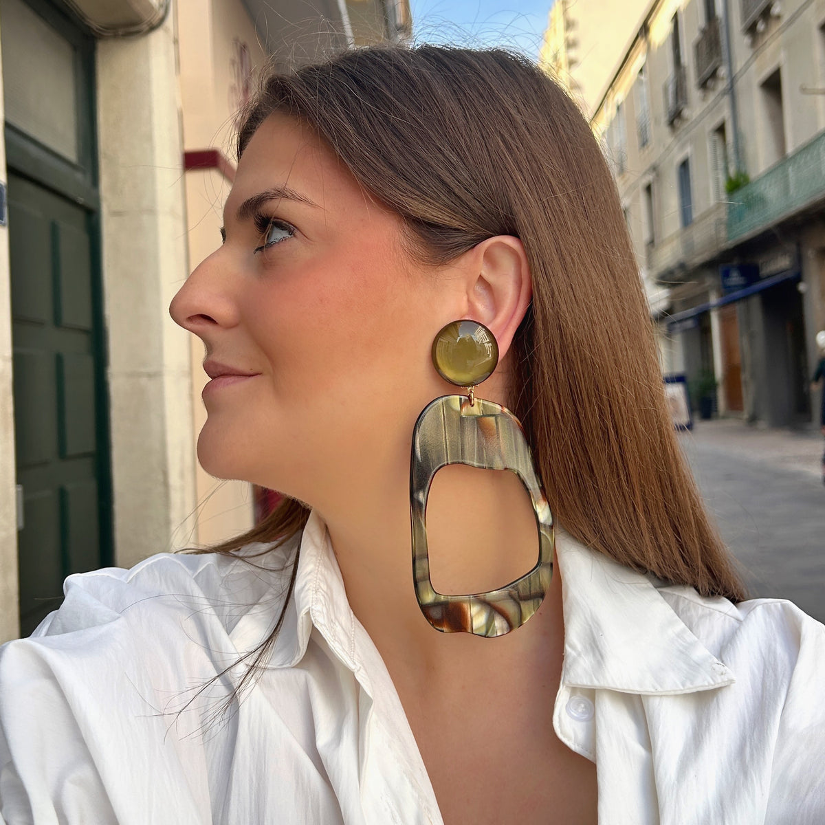 Boucles d’oreilles à clips Nerina Onyx Francine Bramli Paris, cabochons ronds kaki translucide et grands pendentifs géométriques ajourés aux nuances marbrées marron, noir, beige et vert olive.
