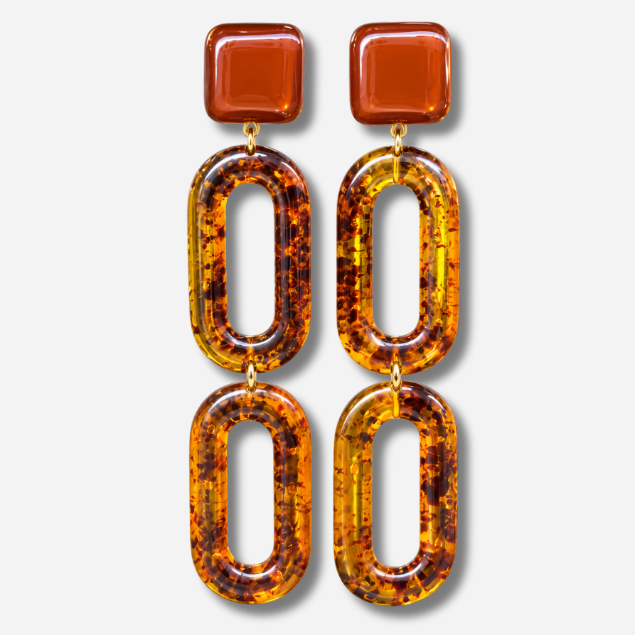 Boucles d’oreilles Noelia Ambre à clips Francine Bramli Paris, cabochons carrés marron translucide et doubles maillons ovales ajourés en résine effet écaille ambrée.