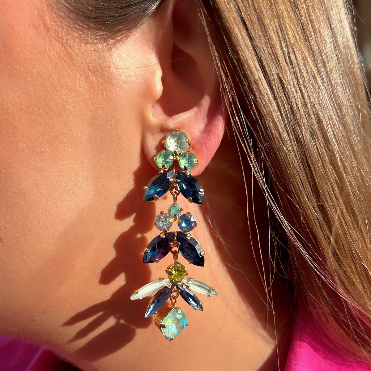 Boucles d’oreilles pendantes Ophéa Blue Crézus, monture dorée ornée de cristaux facettés bleu saphir, bleu ciel, turquoise et vert lime, disposés en cascade avec pierres rondes et marquises.