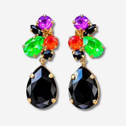 Boucle d’oreille Prisma Fluo Crézus à clips portée à l’oreille, cristaux facettés violet, vert fluo, orange et noir, grande pampille goutte noire sur monture dorée.