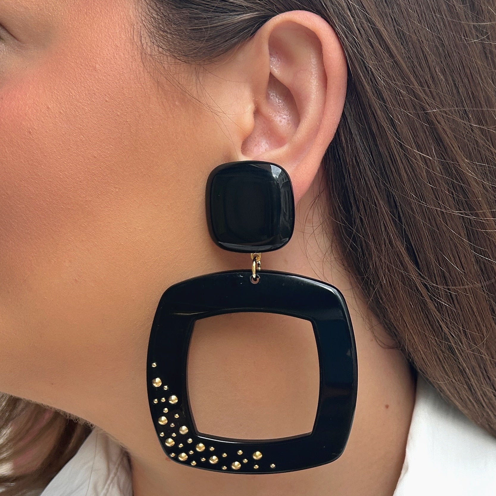 Boucles d'oreilles Reya Noir Clou Francine Bramli en résine noire avec grand carré ajouré et clous dorés