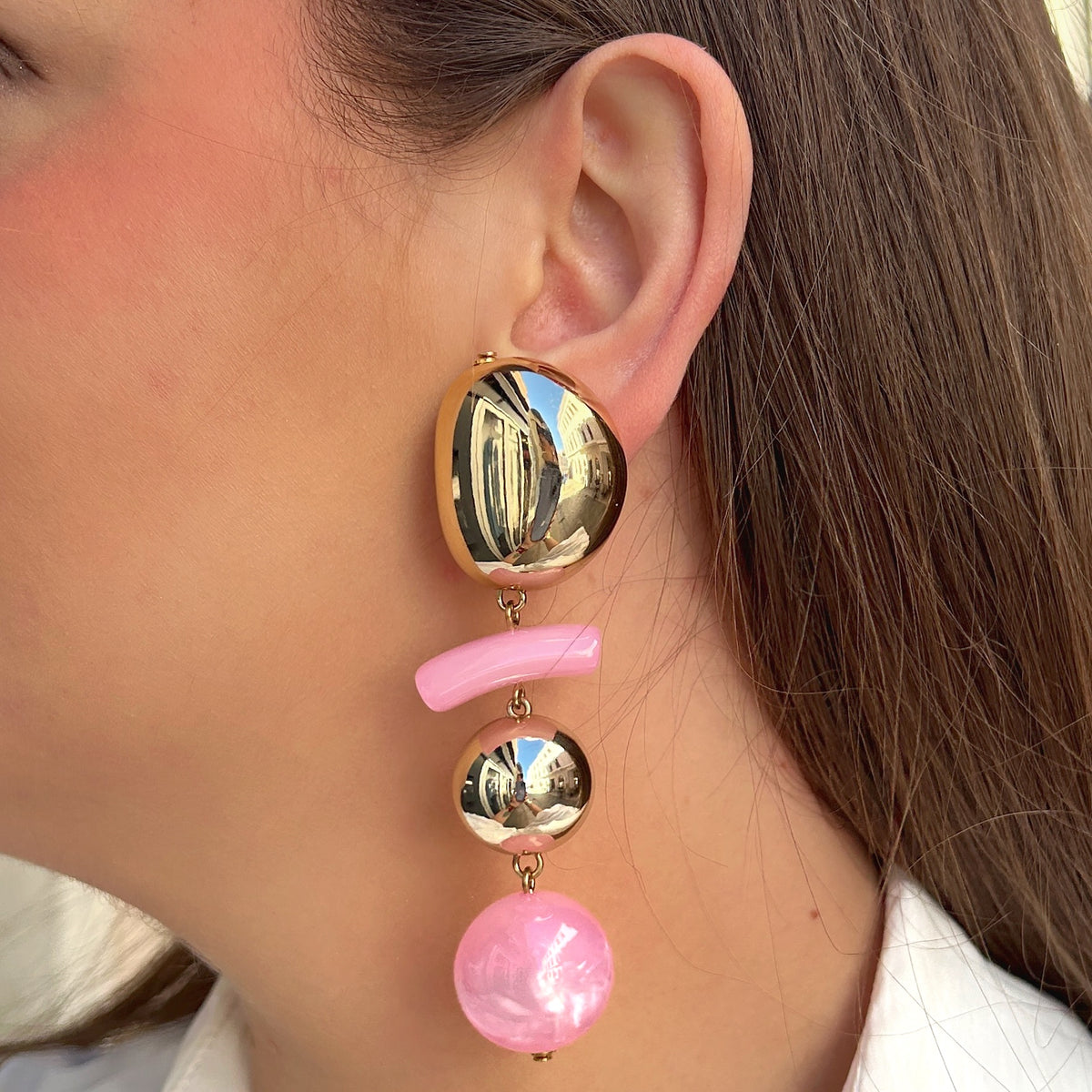 Boucles d'oreilles à clips Rosalia Rose M Francine Bramli Paris avec bouton ovale doré effet miroir, élément incurvé en résine rose pastel, perle ronde dorée et perle rose nacrée – Divinity Sète.
