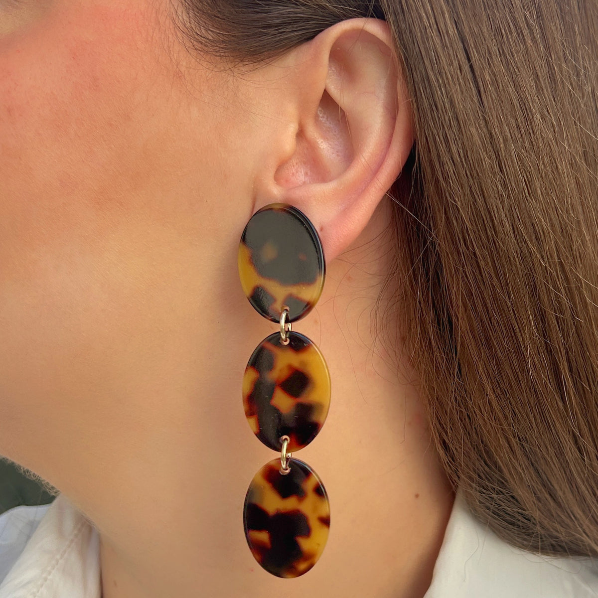 Boucles d’oreilles à clips Solène Écaille de Tokyo Francine Bramli Paris, trois ovales effet écaille marron et ambre reliés par des anneaux dorés.