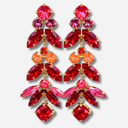 Boucles d’oreilles pendantes Sophéa Red Crézus, monture dorée ornée de cristaux facettés rouge rubis, rose fuchsia et orange, disposés en cascade avec pierres rondes et marquises.