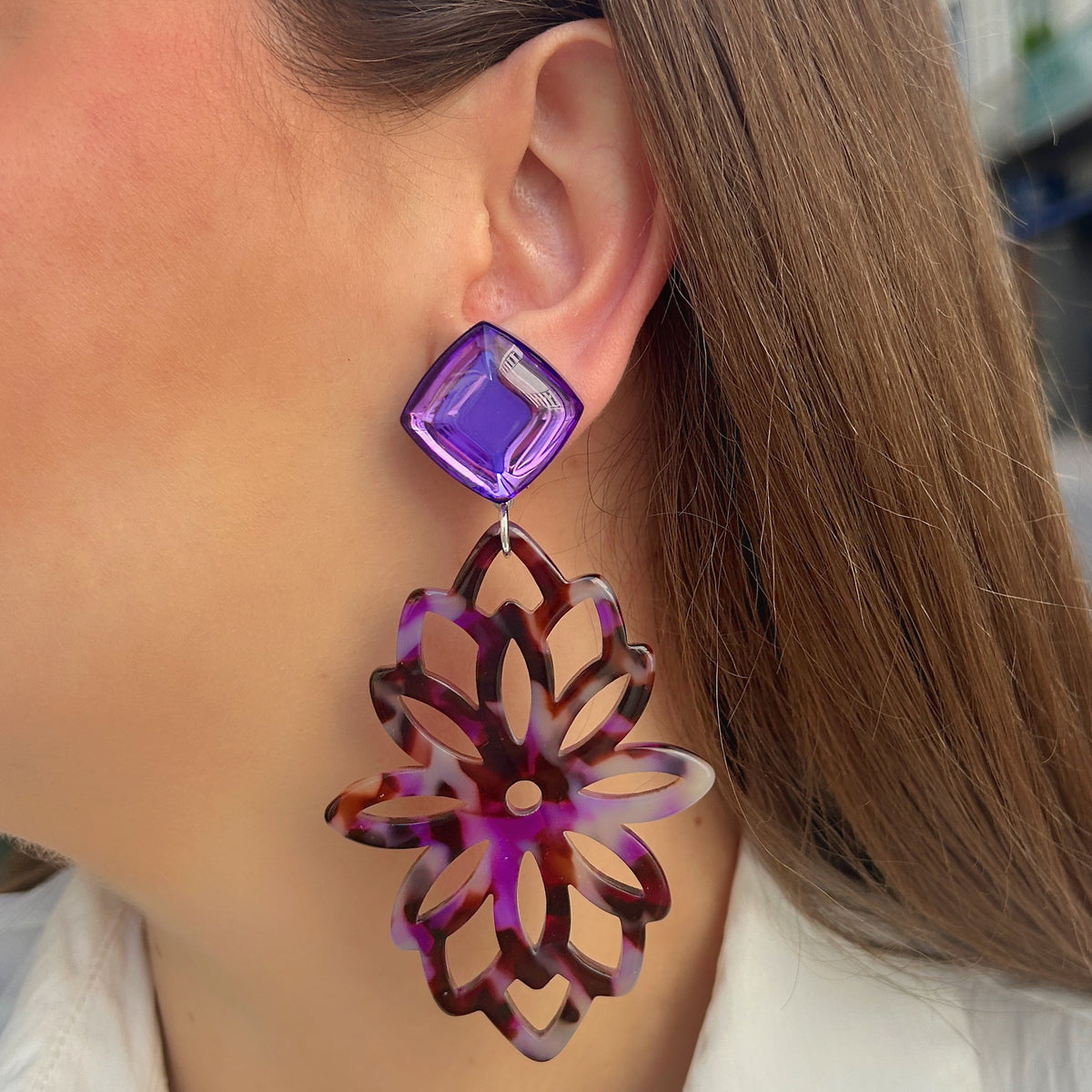 Boucles d’oreilles à clips Sultane Violet Francine Bramli Paris, cabochons carrés en losange violet translucide et grands pendentifs floraux ajourés effet écaille violet, prune, brun et lilas.