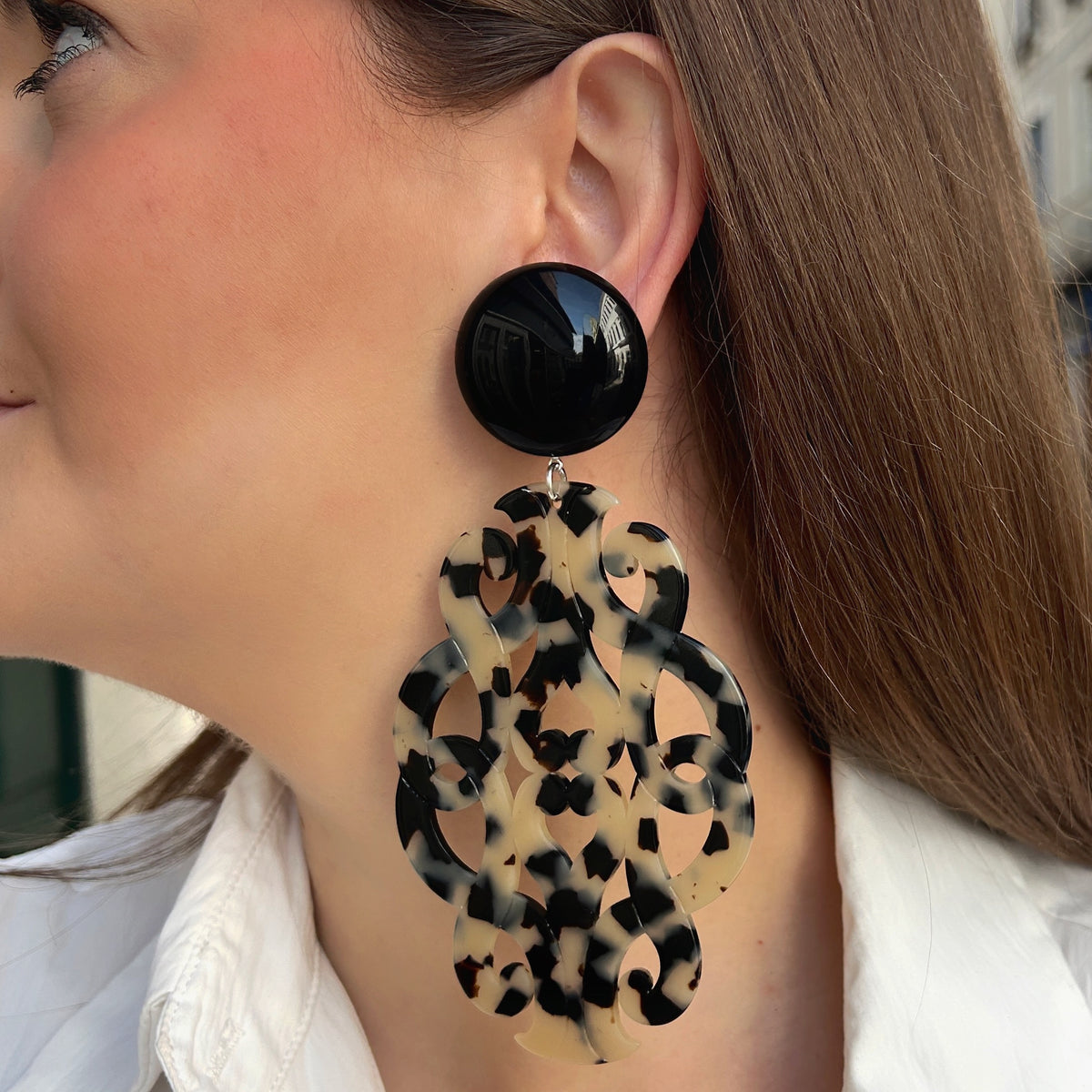 Boucles d’oreilles à clips Sultane XL Écaille Noir et Blanc Francine Bramli Paris, avec cabochon rond noir brillant et grand pendentif baroque ajouré aux motifs écaille noirs et crème.