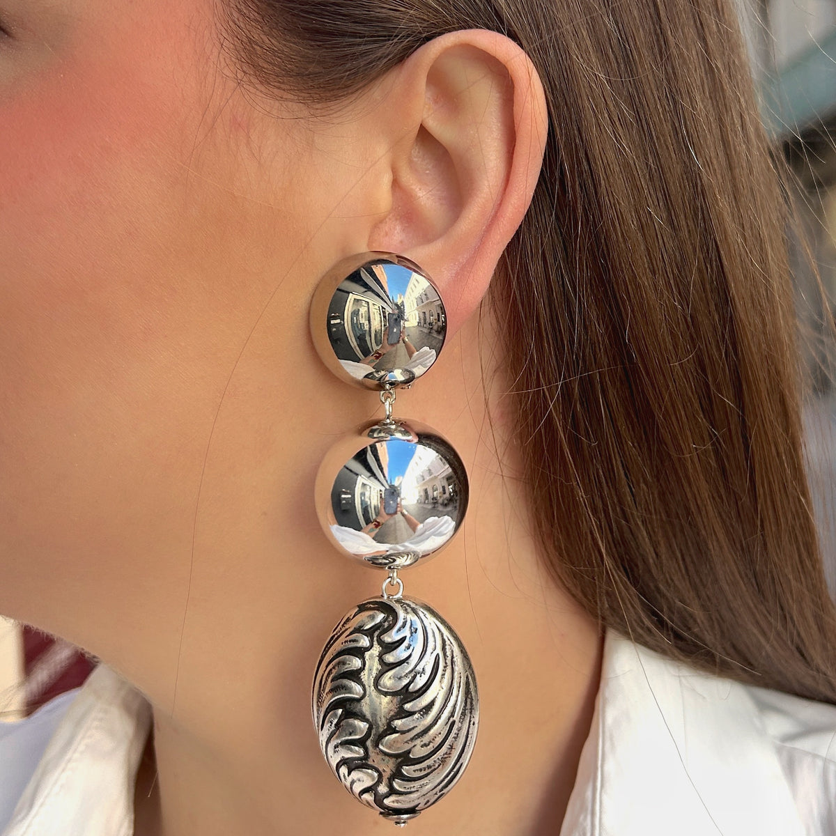 Boucles d'oreilles à clips Sumac Silver Francine Bramli Paris, deux sphères argentées effet miroir et grand pendentif ovale argenté aux motifs sculptés en relief – Divinity Sète.