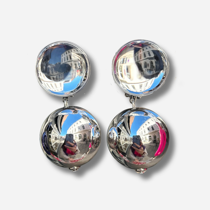 Boucles d'oreilles à clips Thea Silver Francine Bramli Paris, clip rond bombé argenté effet miroir et grande perle sphérique suspendue finition argent brillant – Divinity Sète.