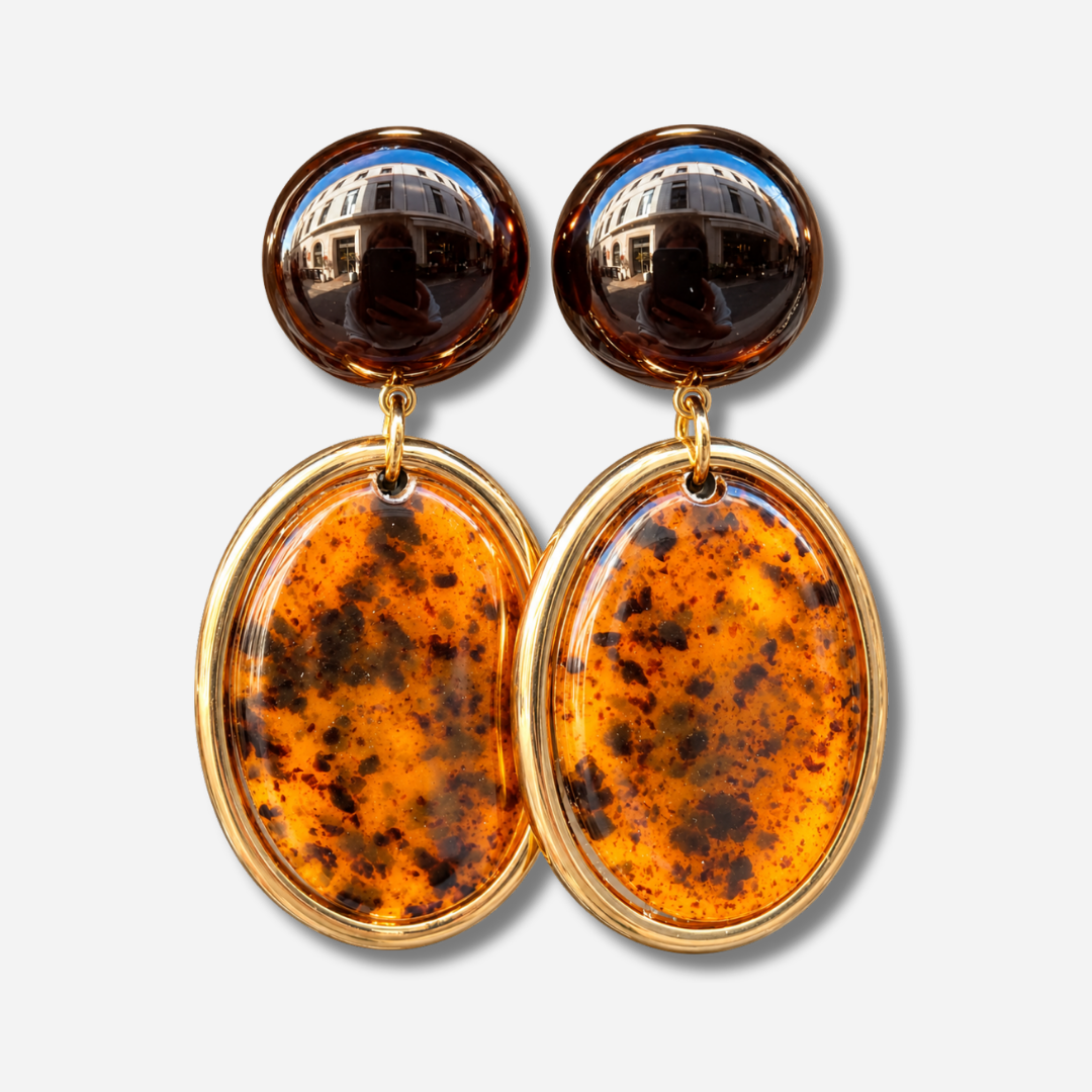 Boucles d’oreilles Tortuga Ambre à clips Francine Bramli Paris, cabochons ronds brun foncé et grands pendentifs ovales ambre orangé moucheté de brun avec contour doré.