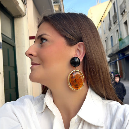 Boucles d’oreilles Tortuga Ambre à clips Francine Bramli Paris, cabochons ronds brun foncé et grands pendentifs ovales ambre orangé moucheté de brun avec contour doré.