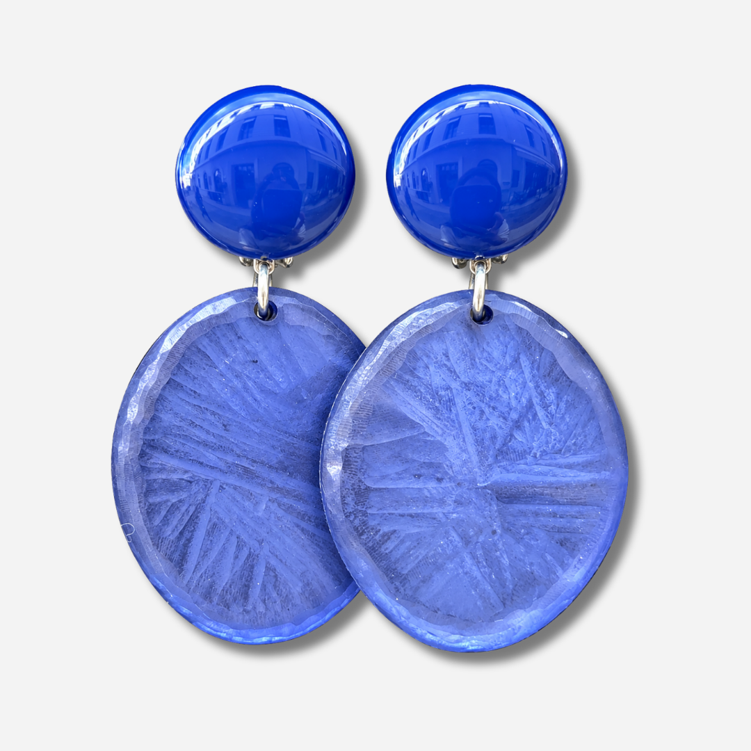 Boucles d’oreilles Tortuga Bleu à clips Francine Bramli Paris, cabochons ronds bleu électrique brillant et grands pendentifs circulaires bleu lavande texturés, reliés par des anneaux argentés.