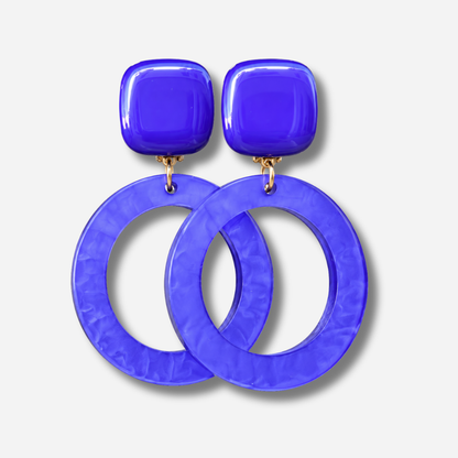 Boucles d’oreilles Veronica M Violet à clips Francine Bramli Paris, cabochons carrés violets et grands anneaux circulaires ajourés.