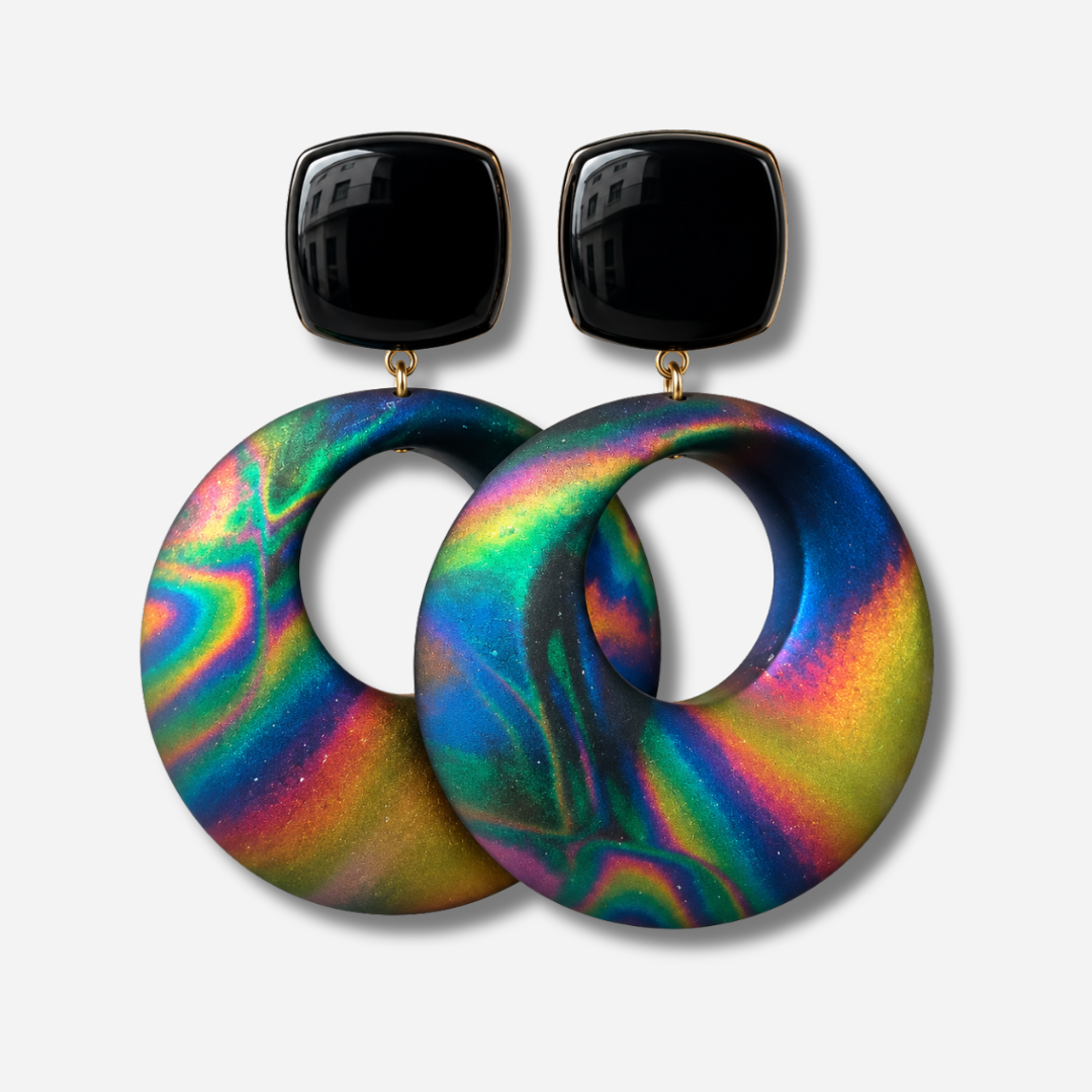 Boucles d’oreilles Vivianne Rock à clips Francine Bramli Paris, cabochons carrés noirs brillants et grands anneaux ronds ajourés aux reflets irisés bleu, vert, violet, rose et doré.