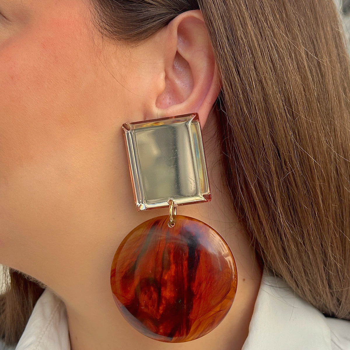Boucles d’oreilles Zoé Marron Miroir à clips Francine Bramli Paris, cabochons carrés miroir argenté avec bordures translucides ambrées et grands pendentifs ronds marbrés marron, cognac et ambre, Divinity Sète.