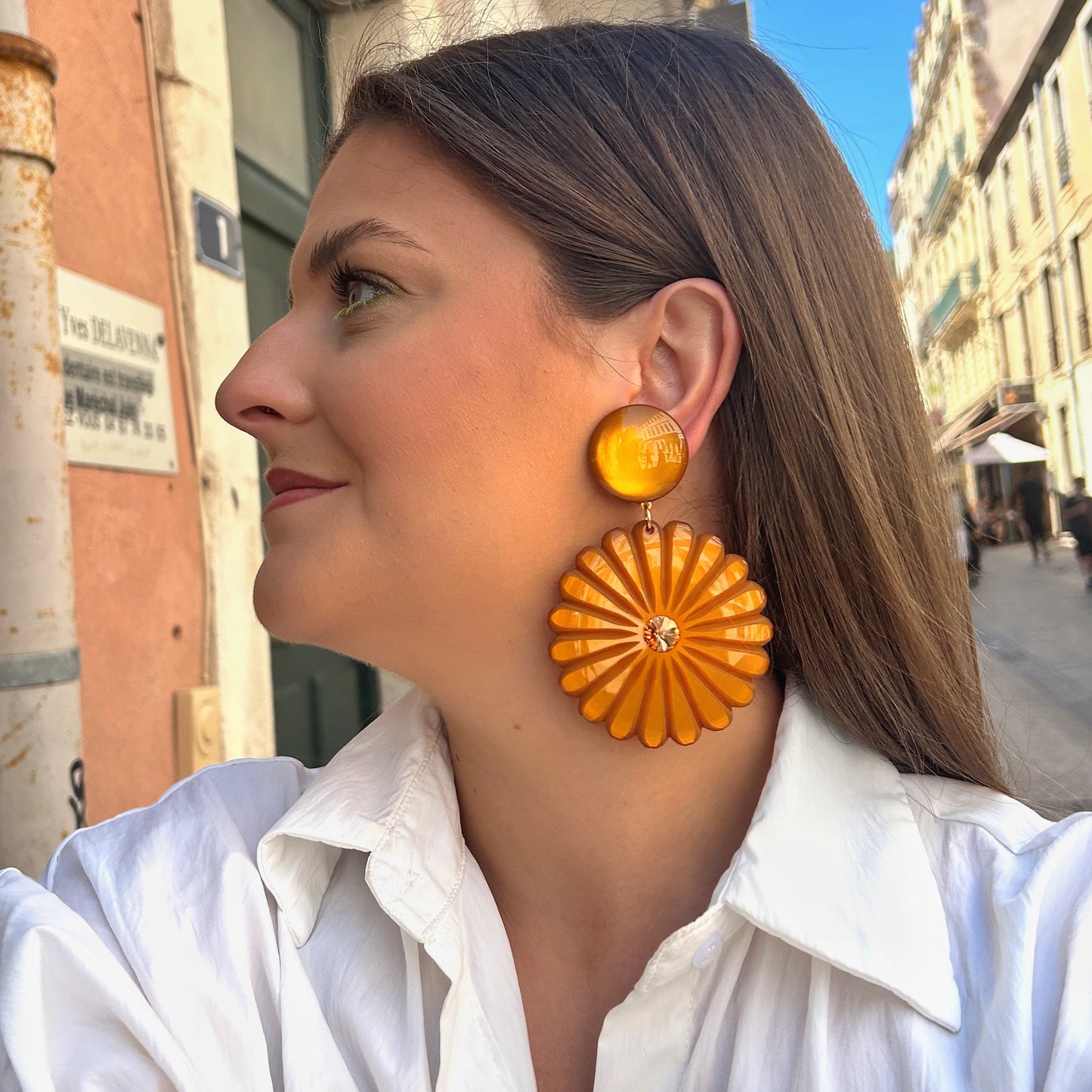 Boucles Pensée Ocre Francine Bramli Paris en résine ocre sculptée en forme de fleur avec cristal central doré.