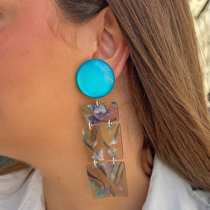 Boucles Romane Francine Bramli Paris en résine marbrée bleu turquoise et nacrée avec design graphique articulé.