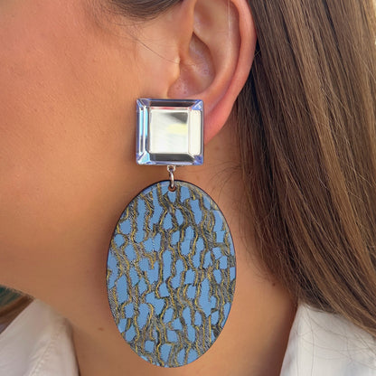 Boucles Solal Bleu Francine Bramli Paris avec cabochon carré bleu translucide et pendentif ovale graphique bleu et doré.