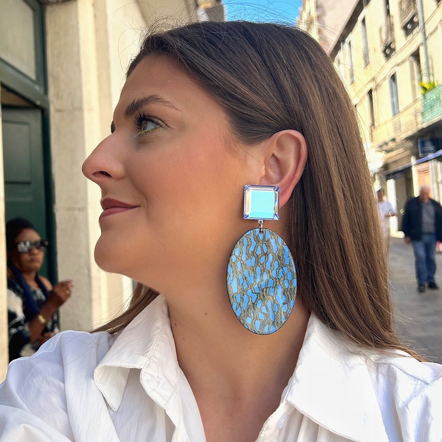 Boucles Solal Bleu Francine Bramli Paris avec cabochon carré bleu translucide et pendentif ovale graphique bleu et doré.