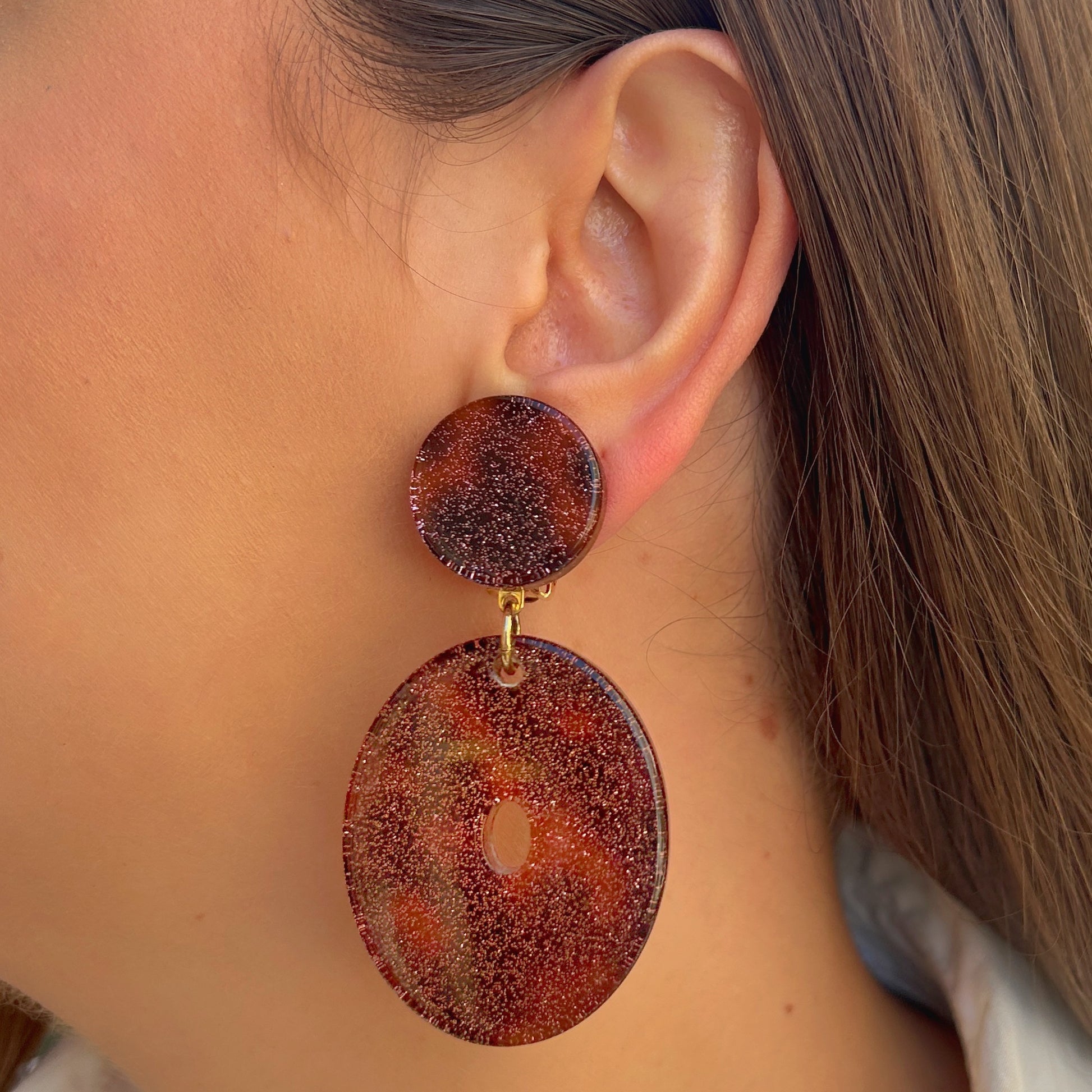 Boucles Vega Francine Bramli Paris en résine pailletée rose cuivré portées sur oreille