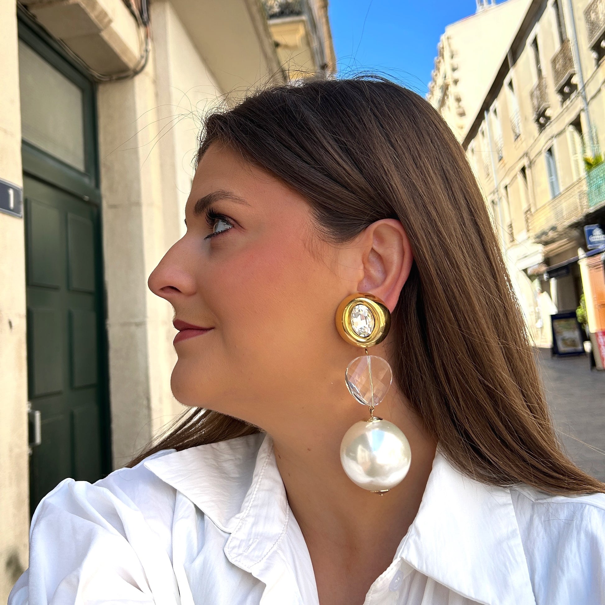 Boucles Yaelle Perles Francine Bramli Paris avec cristal transparent, monture dorée et grande perle nacrée blanche pendante.