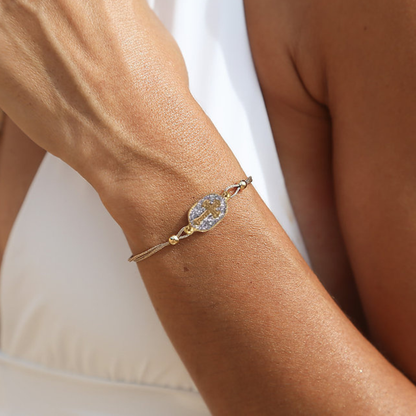 Bracelet Nonza Croix Argent Amadrina sur cordon réglable avec croix dorée, pavage de paillettes argentées et perle de corail naturelle