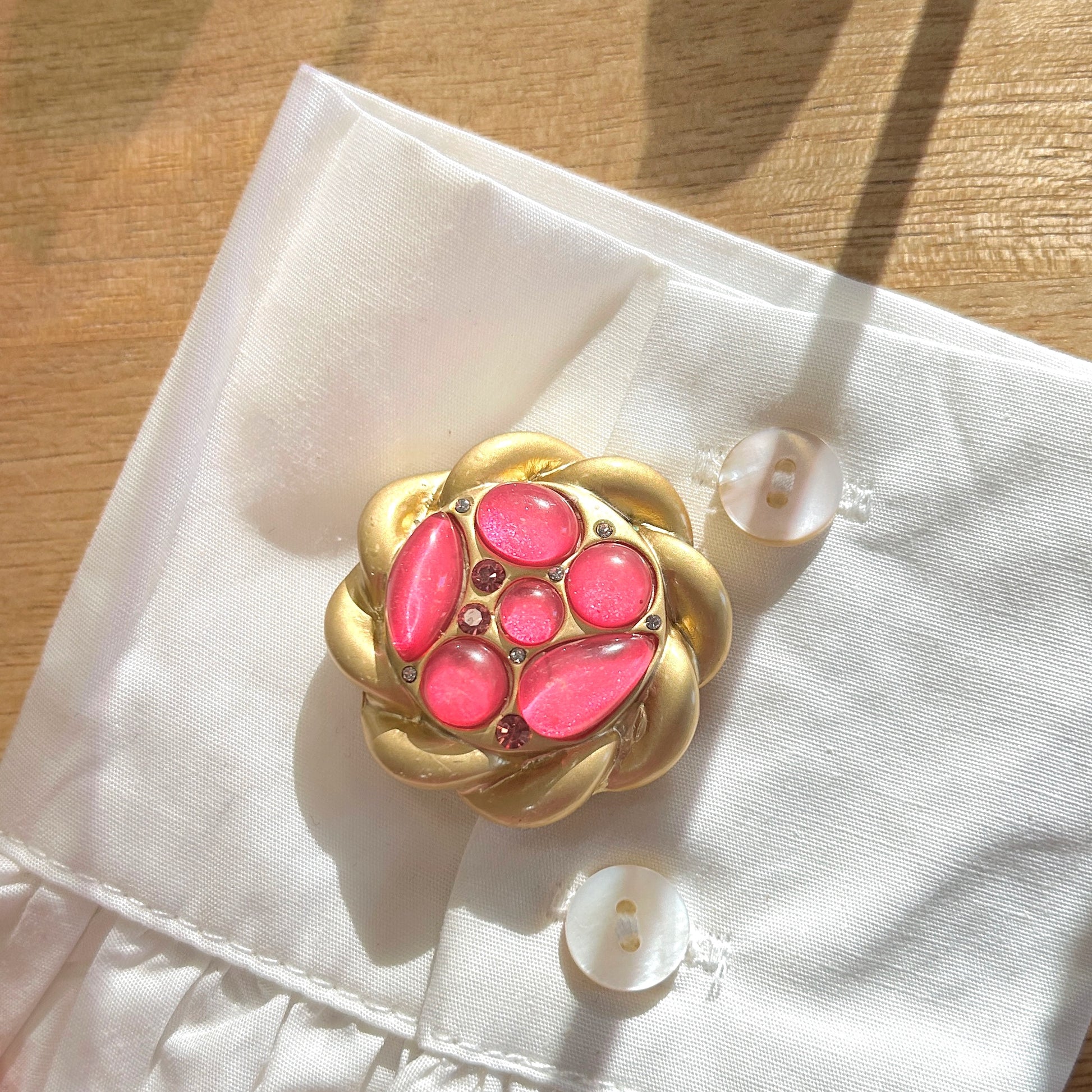 Détail de la broche bouton rose cabochons et strass