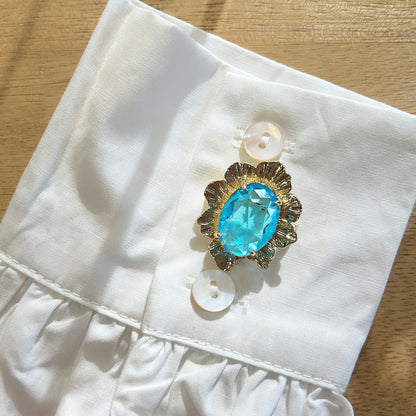 Broche bijou femme corolle dorée avec pierre centrale bleu
